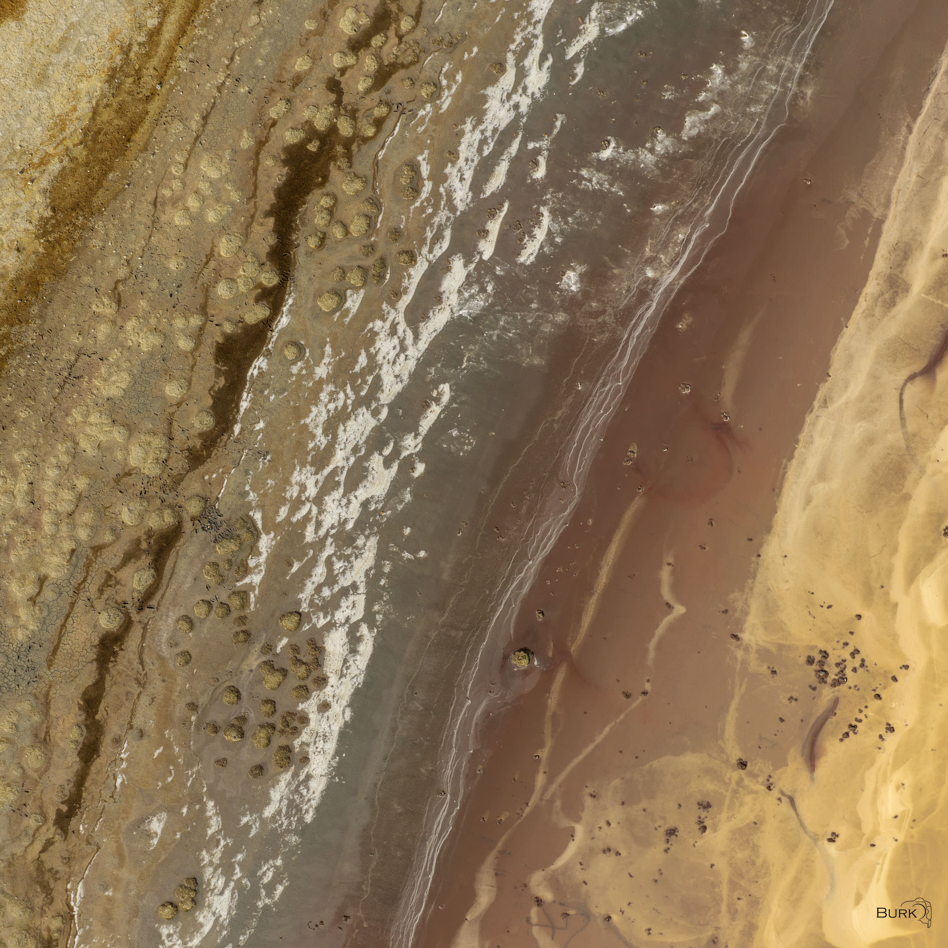 Remnants of the Lake Square Aerial photo of the Great Salt Lake showing exposed shoreline, mineral deposits, shallow water, and abstract patterns in gold, brown, and gray. Square crop.