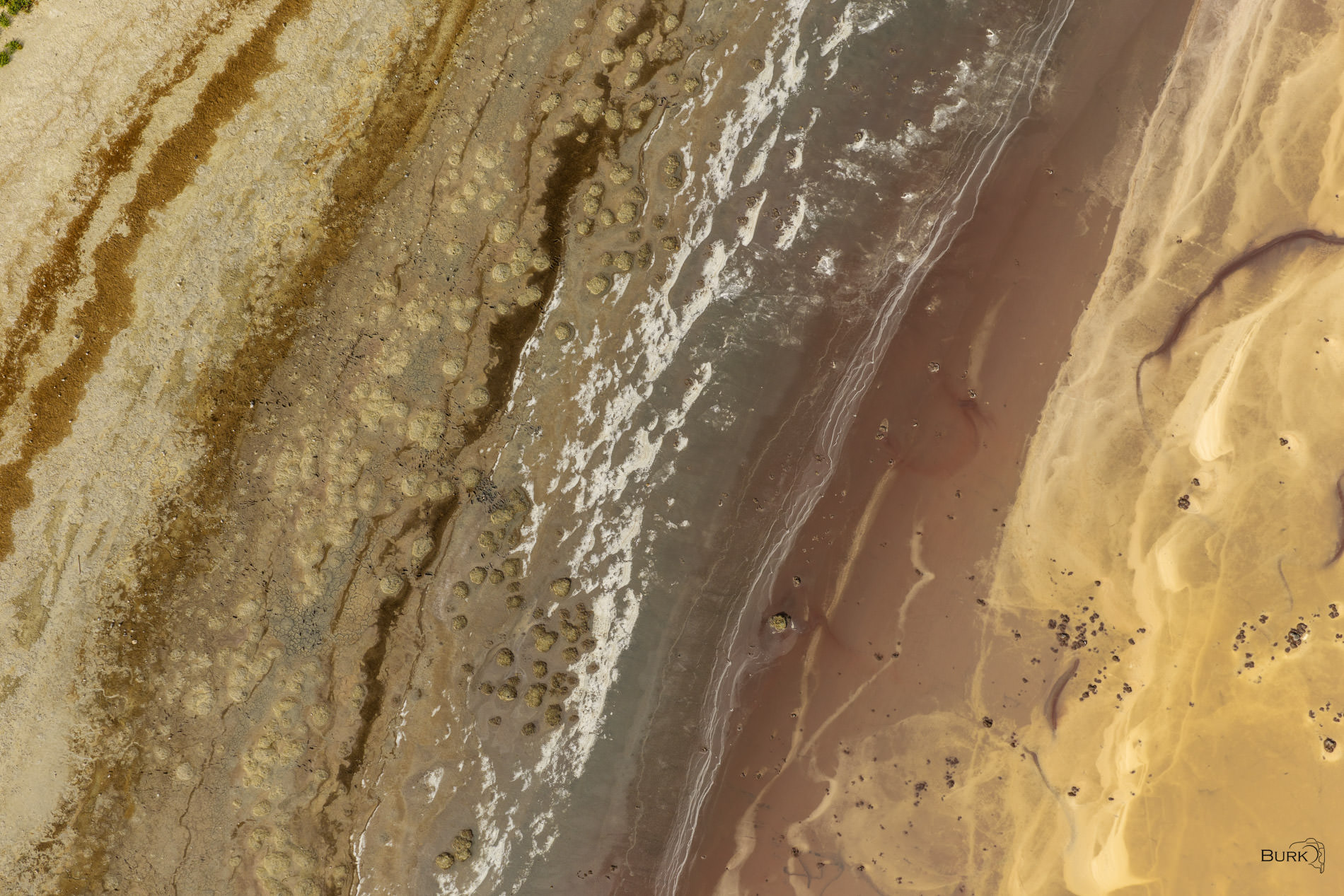 Remnants of the Lake Aerial photo of the Great Salt Lake showing exposed shoreline, mineral deposits, shallow water, and abstract patterns in gold, brown, and gray.