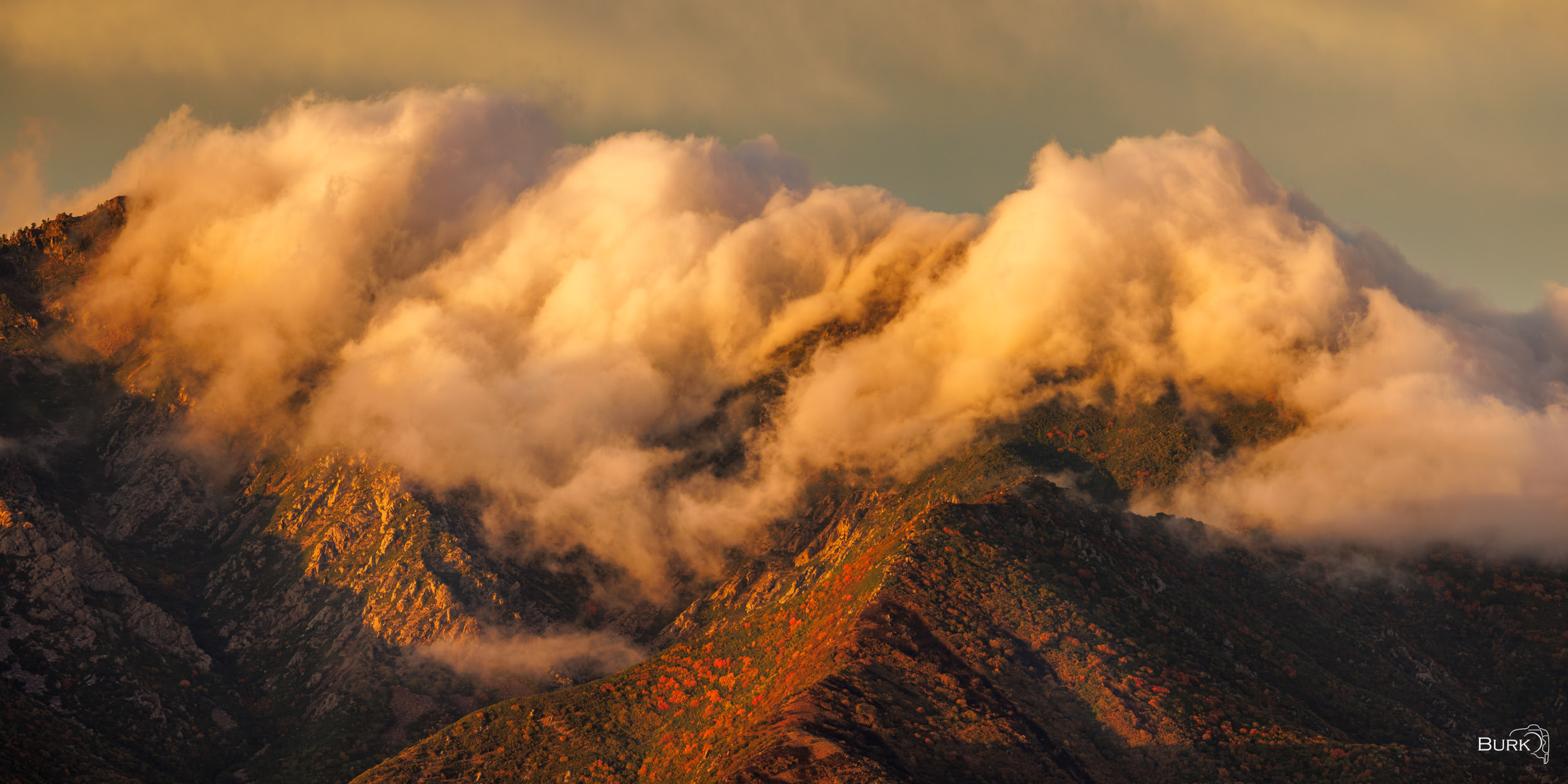 Strawberry Peak Strawberry Peak near Huntsville, Utah, glowing in golden evening light as low clouds drift across the rugged, autumn-colored mountainside.